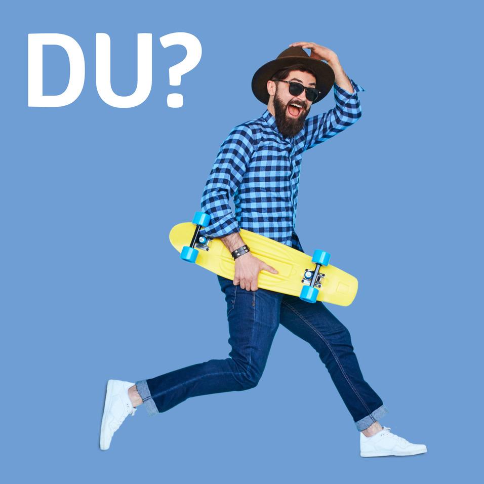 Mann in kariertem Hemd und Hut springt mit gelbem Skateboard vor blauem Hintergrund und fragt: "DU?"